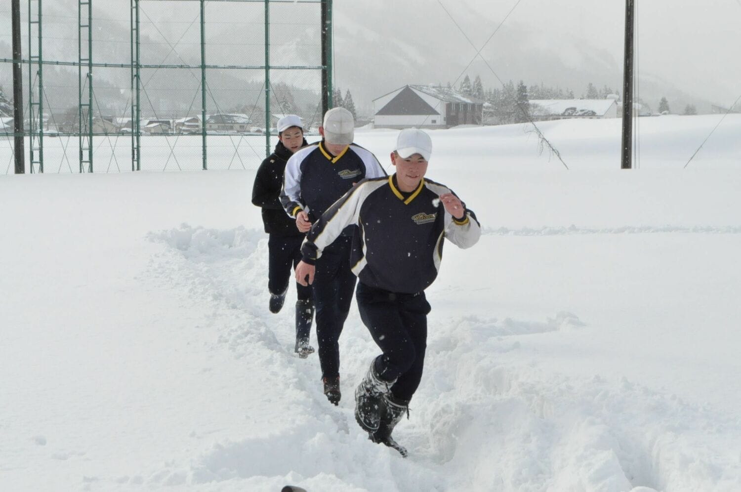 グラウンドに積もった雪の上を全力疾走する主将の吉津塁ら（2022年撮影） ©KYODO