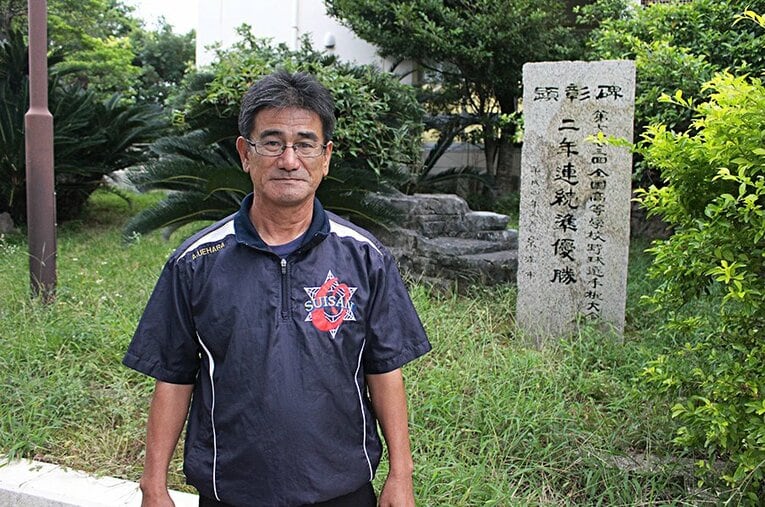 甲子園準優勝記念碑の前で写真に収まる上原忠監督。沖縄の球児たちとともに「甲子園請負人」が22年ぶりの夏を目指す。 ／ photograph by Yu Takagi