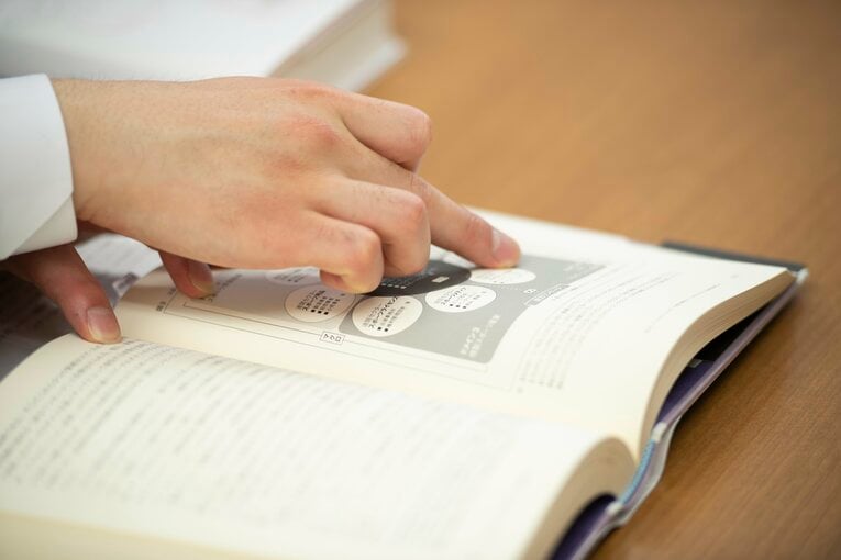 研究者として自身でまとめた論文を示しながら、フィギュアスケート産業について詳細に説明する町田