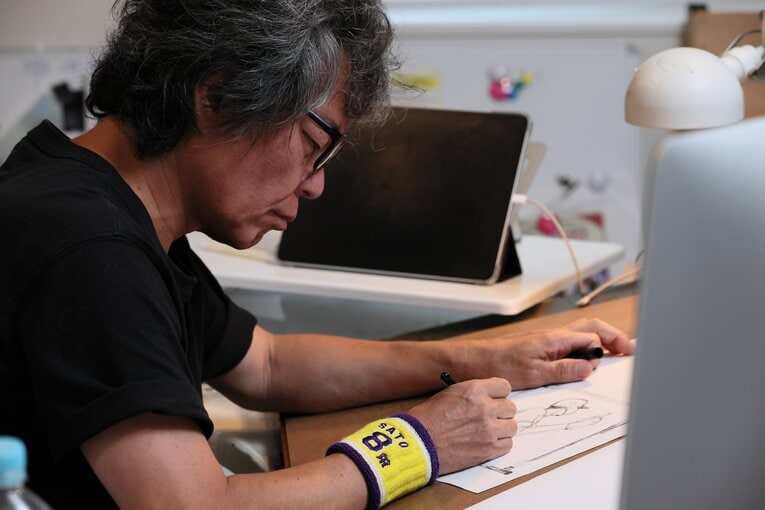 「SATO 8」と刺繍されたリストバンドをつけ、サラサラと佐藤輝明のホームランシーンを描く髙橋氏　©Shigeki Yamamoto