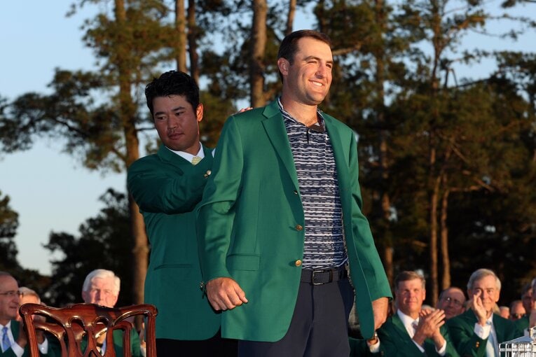 今年4月に2度目のマスターズ制覇を達成したスコッティ・シェフラー。初優勝した2022年には、前年度王者の松山英樹（左）からグリーンジャケットを受け取ったが、まさかその2年後に囚人服を着せられるとは…　©︎Getty Images