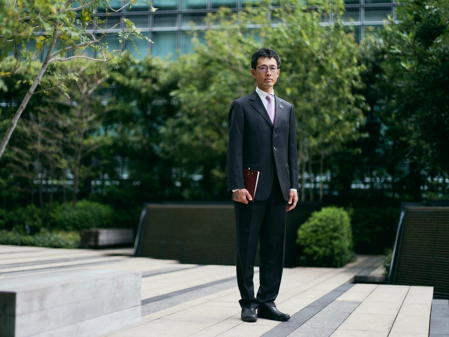 大手町の街にすっかり馴染むスーツ姿の木佐貫さん。身につけているスーツとネクタイはいずれも思い出の品だ　©Yuki Suenaga