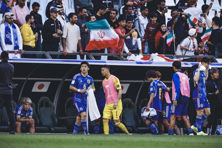 ベンチから立ち上がらず、ピッチのほうを見つめる堂安　©Kiichi Matsumoto