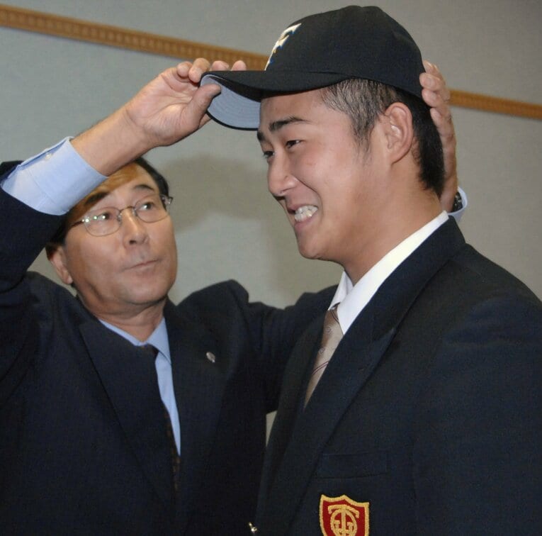 指名あいさつに訪れ、大阪桐蔭高の中田翔（右）に日本ハムの帽子をかぶせる高田繁GM　©JIJI PRESS