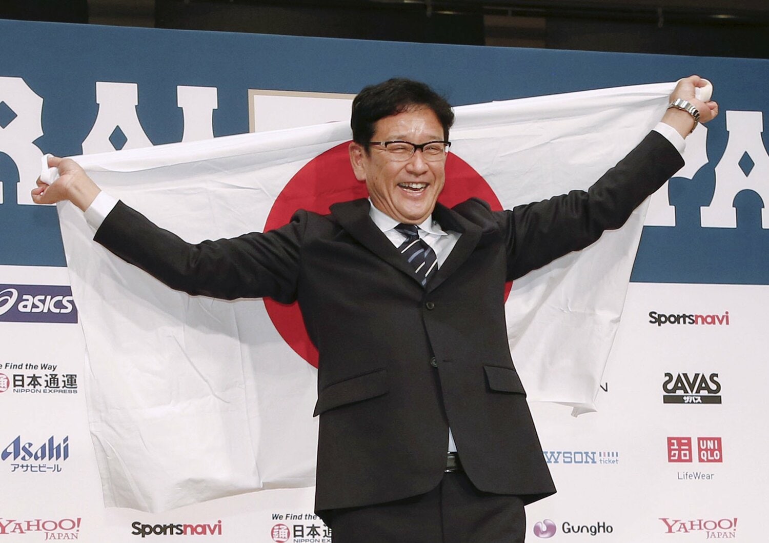 侍ジャパン監督就任の会見で日の丸を広げる栗山英樹（2021年12月2日）©️KYODO