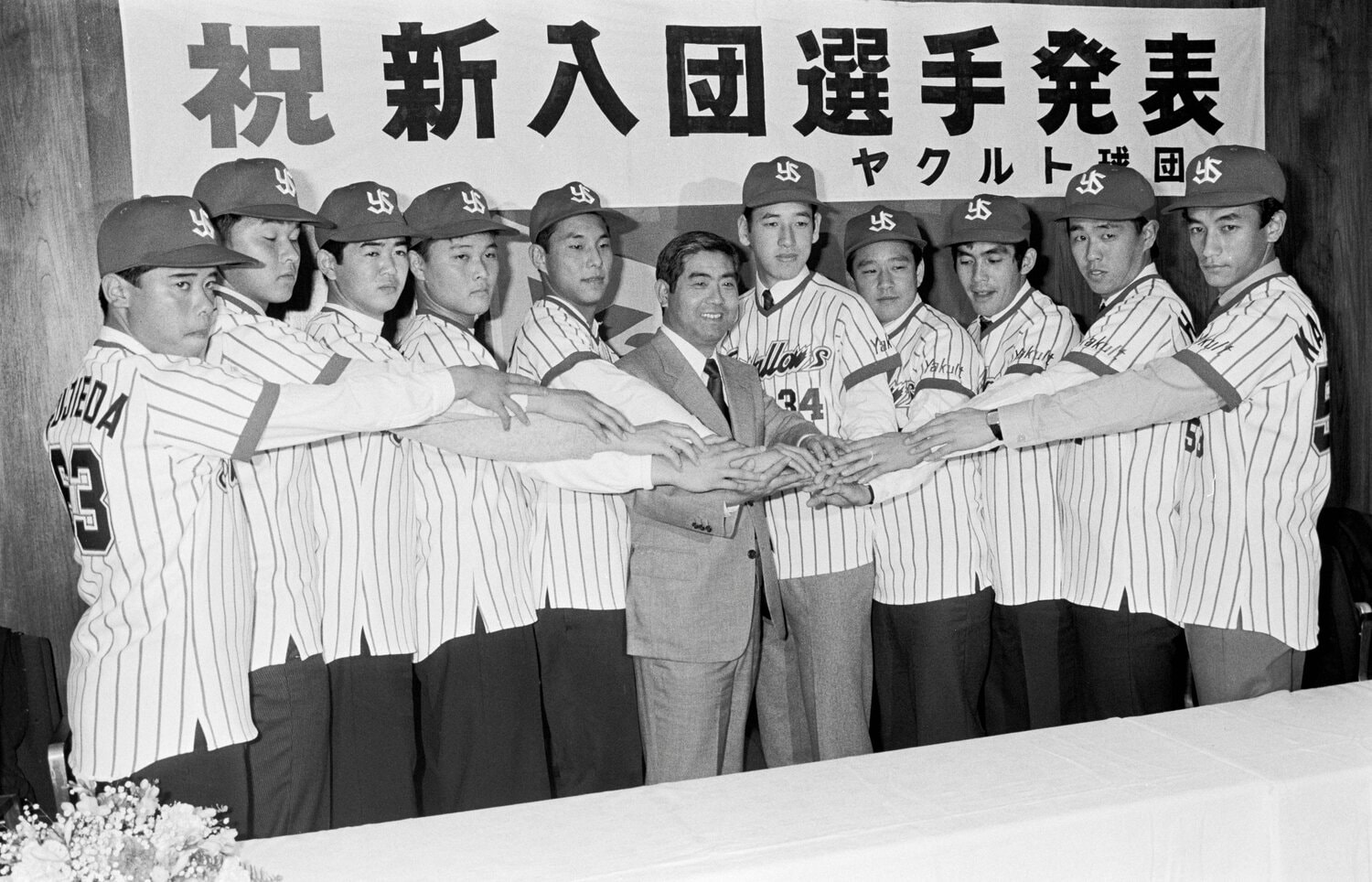 ヤクルトスワローズの新入団発表で武上四郎監督（中央）と手を合わせる栗山英樹（右から４人目）、ドラフト1位の高野光（同５人目）、2位の池山隆寛（左から５人目）などがいる　©JIJI PRESS