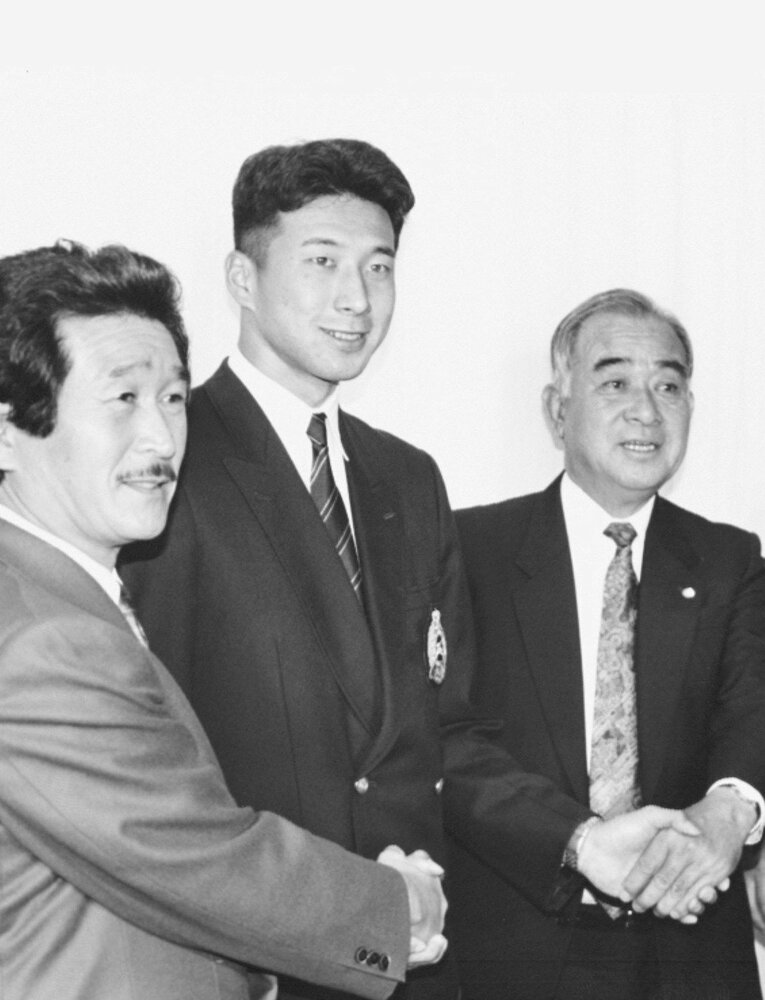 史上初の逆指名で巨人にドラ1入団した三野。東北福祉大の大竹野球部長（左）と巨人の加藤スカウト（右）　©KYODO