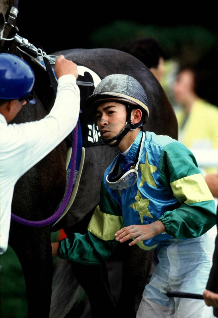 パドックで騎乗前に馬の腹帯に手をやる　©Keiji Ishikawa