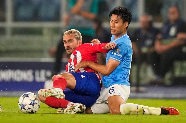 アトレティコのエースであるグリーズマンと競り合う鎌田大地。ラツィオはGKのヘディングシュートという形で勝ち点1を確保した ／ photograph by AP/AFLO