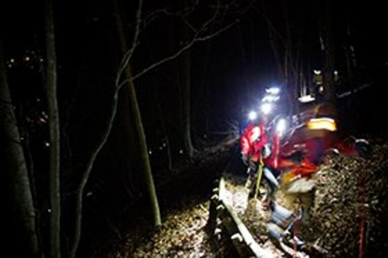 夜間、ヘッドライトをつけて山道を走っていくランナーたち。