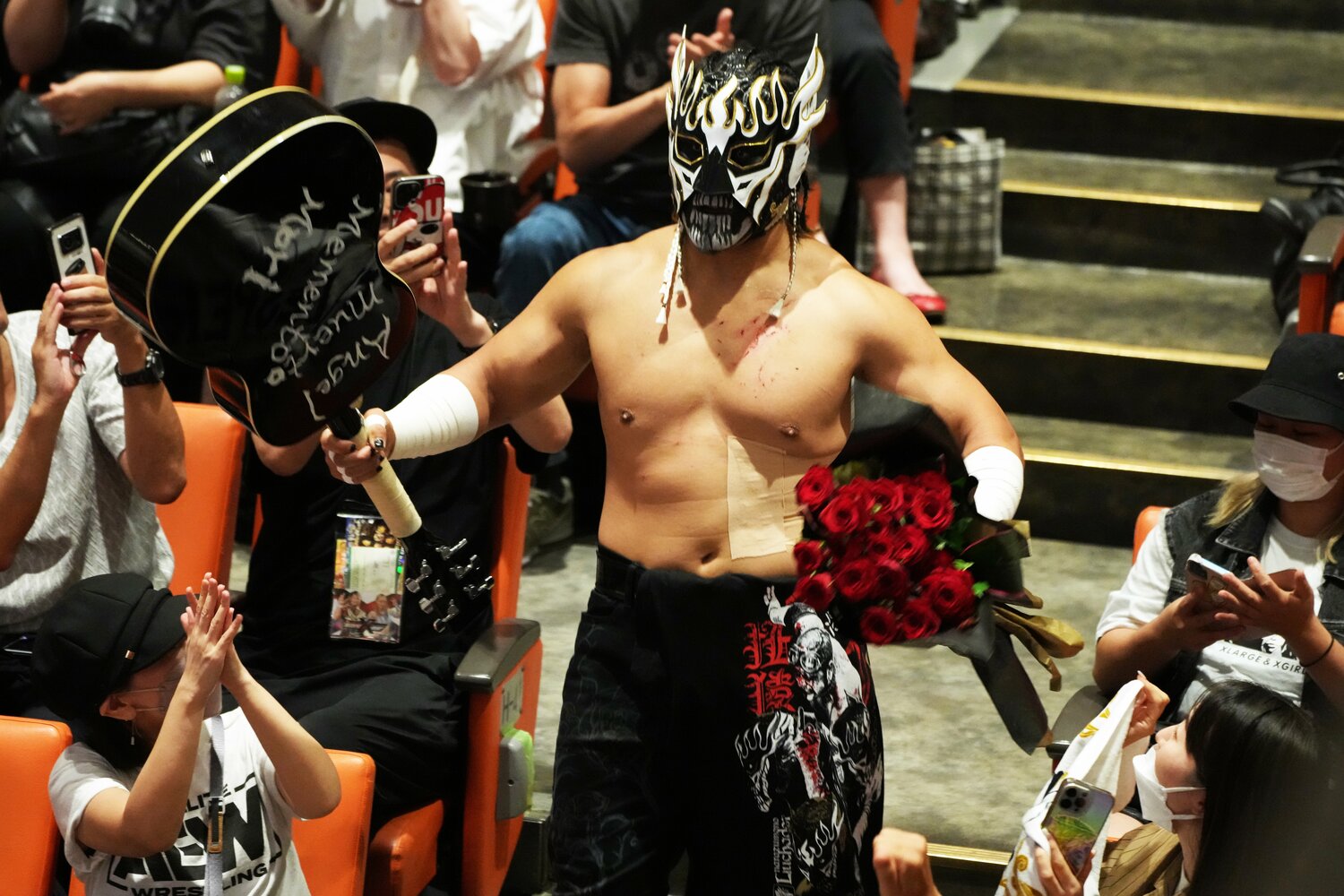 7月5日、バラの花束とギターを手に客席から入場するエル・デスペラード。花束にはチーズスライサーが仕込まれていた（クリックすると「この記事の写真」に飛びます。流血等の過激な写真を含みますのでご注意ください）