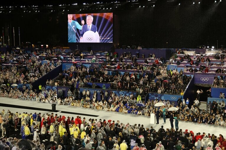 バッハ会長は傘をさしてもらいながらスピーチ　©Tetsuya Higashikawa/JMPA