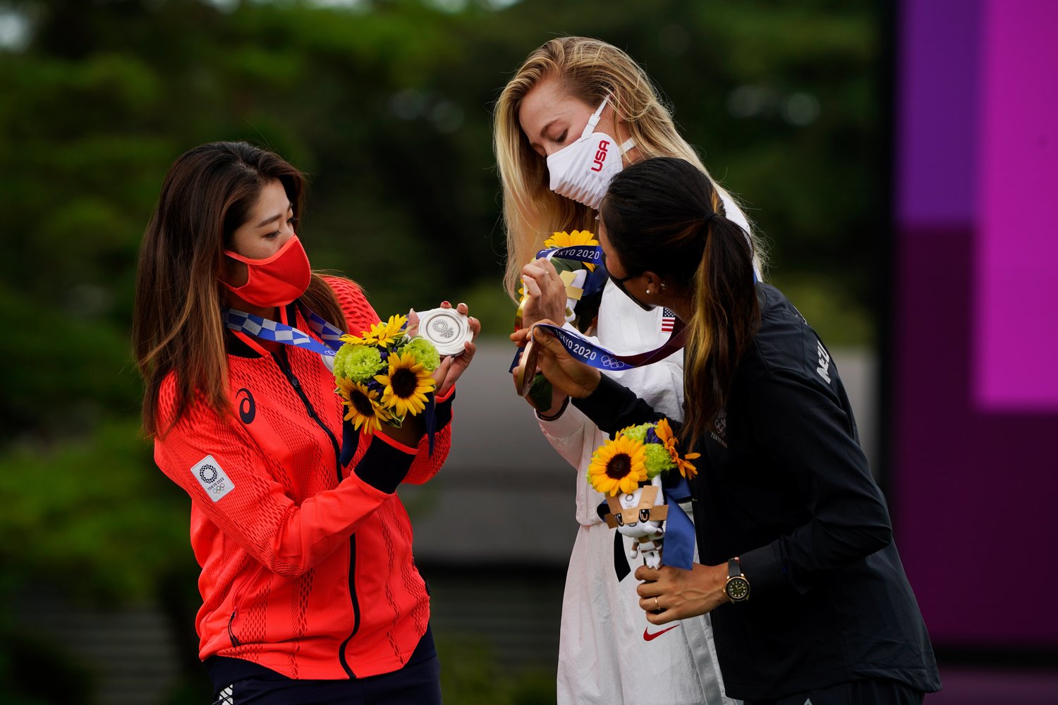 ともに表彰台に上がったネリー・コルダ（中央）、リディア・コ（右）とメダルを確かめ合う稲見萌寧　©︎Shizuka Minami