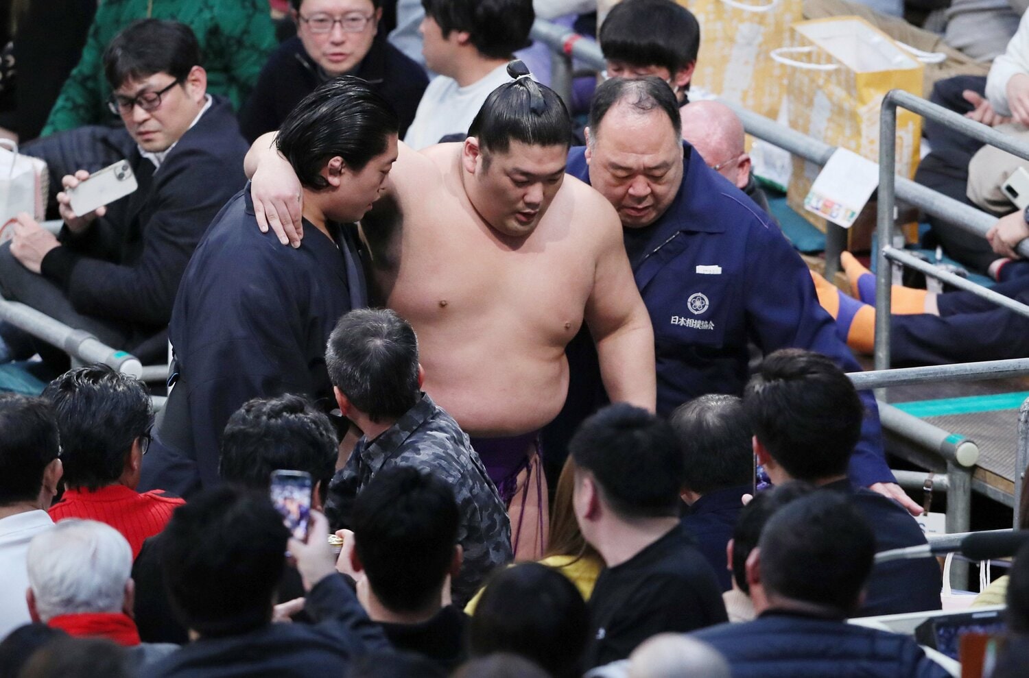 春場所14日目、朝乃山戦で右足首を負傷した尊富士。自力で歩行できず肩を借りて退場する　©JIJI PRESS