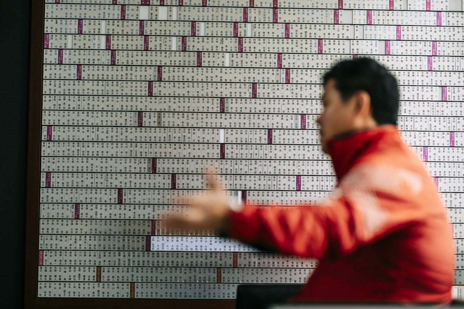 歴代の選手たちの名前が飾られたボードの横でインタビューに応じた大田尾監督　©︎Kiichi Matsumoto