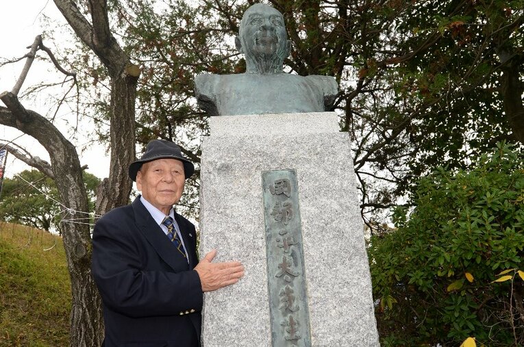 福岡市の平和台陸上競技場にある岡部平太の胸像前で写真に収まる生前の田中茂樹。恩師の教えを胸に、91年の生涯を閉じた ／ photograph by Koh Tanaka