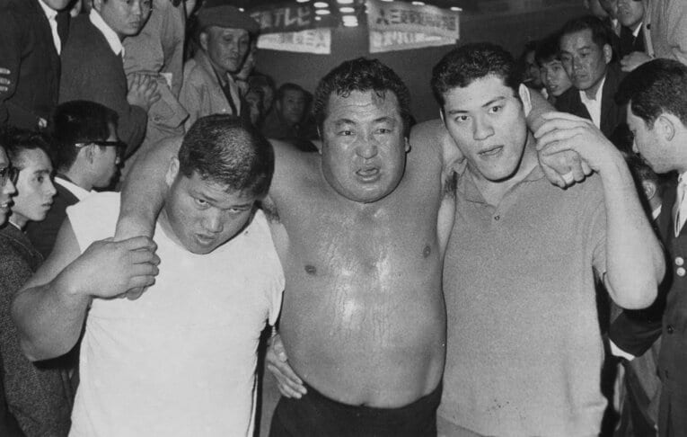 力道山vsデストロイヤー。豊登（左）と アントニオ猪木（右）に助けられ、会場を後にする力道山　©Sankei Shimbun