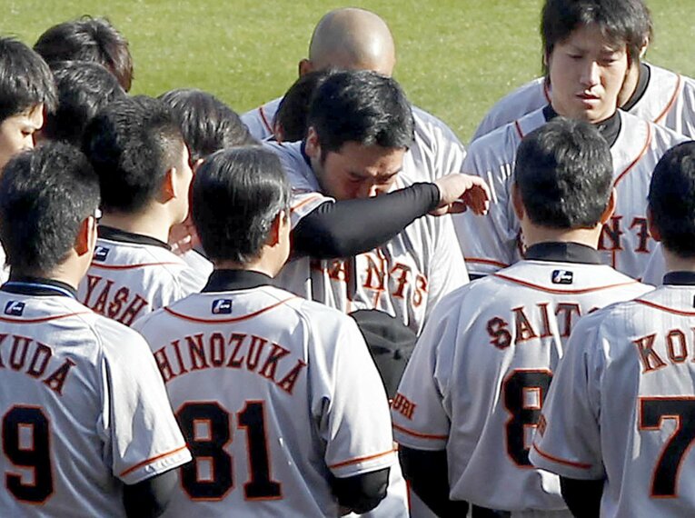 練習前に木村拓也コーチの冥福を祈り黙とうし涙をぬぐう阿部慎之助（中央）ら巨人ナイン（2010年4月）　©KYODO