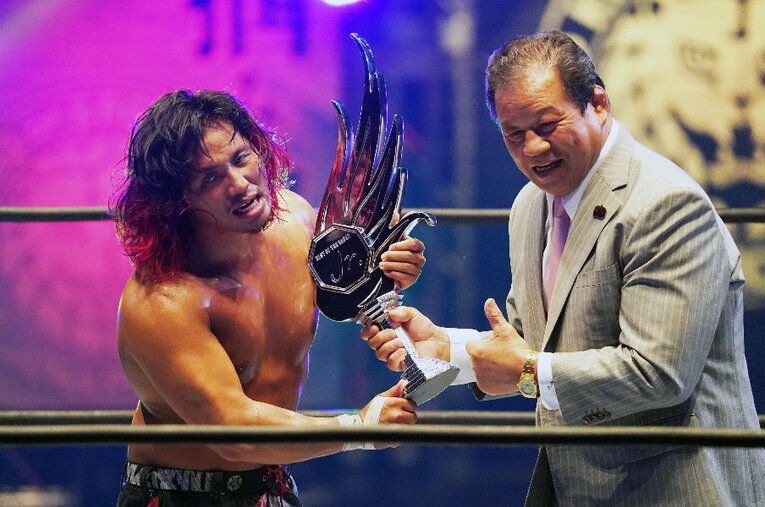 エル・デスペラードとの30分超の熱戦を制し、史上初の3連覇＆史上最多4度目の『BOSJ』優勝を果たした高橋ヒロム。藤波辰爾からトロフィーを手渡される ／ photograph by Essei Hara