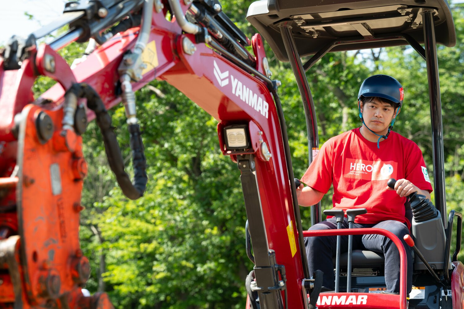 ヘルメット姿で重機を操る小塚　©︎Tadashi Hosoda