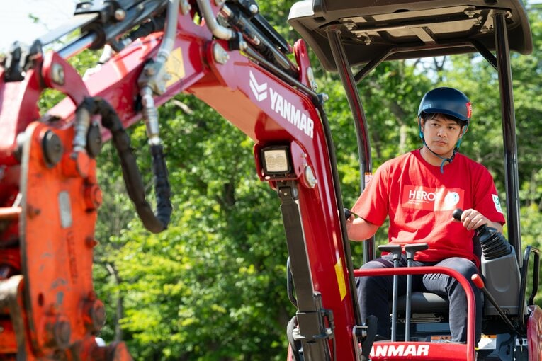 ヘルメット姿で重機を操る小塚　©︎Tadashi Hosoda