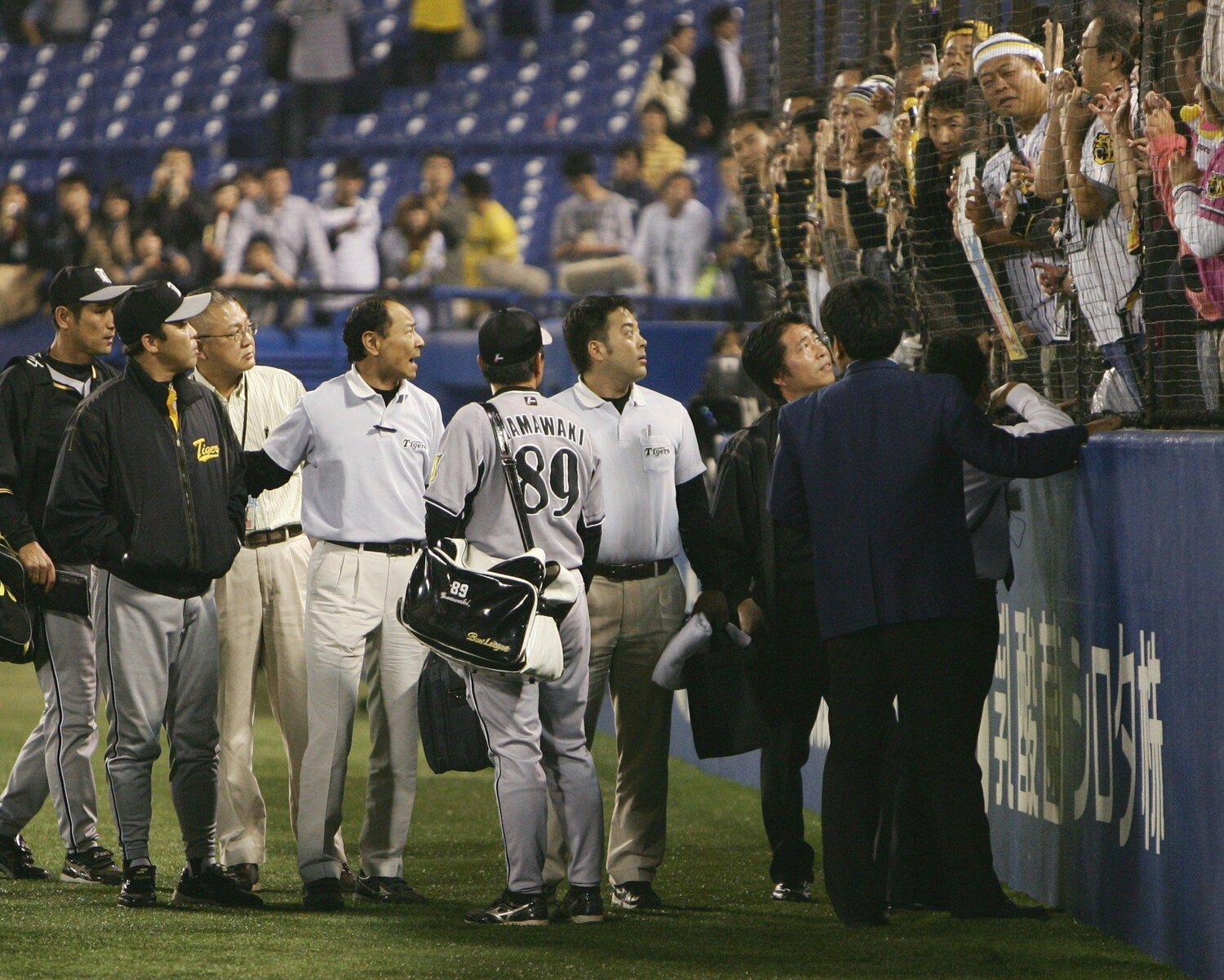 2008年10月4日ヤクルトと引き分け、三塁側の阪神ファンの前を通って引き揚げる岡田彰布監督(左から2人目)。ファンの野次に怒り、厳しい表情で観客席をにらむ ©JIJI PRESS