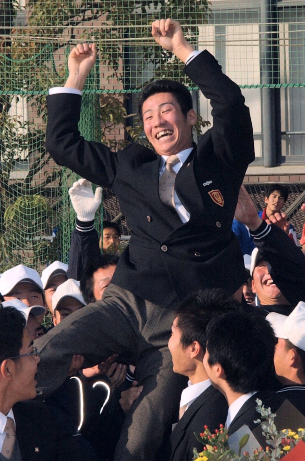 ロッテに1巡目指名を受けてチームメイトに担がれる西岡（2002年11月）©️KYODO
