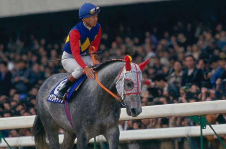 武豊を背に、満員の競馬場を歩くオグリキャップ。「ウマ娘」でも人気を集める名馬の子孫たちの活躍は？ ／ photograph by Tomohiko Hayashi