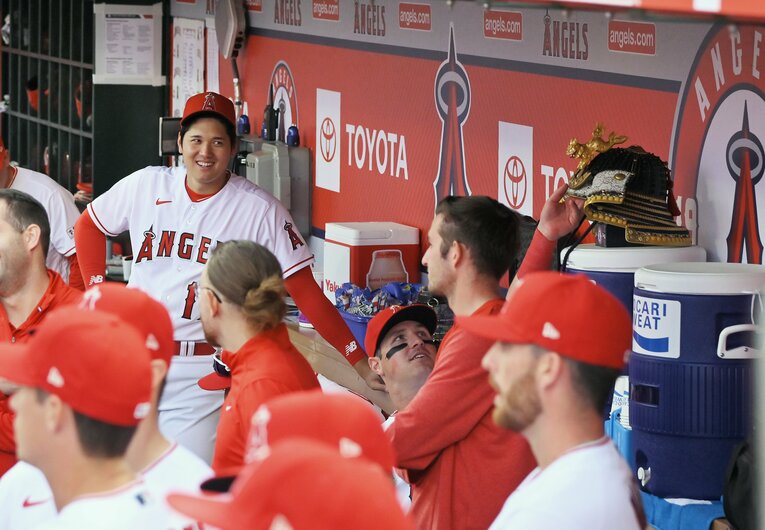 ベンチで兜を見て笑う大谷　©JIJI PRESS