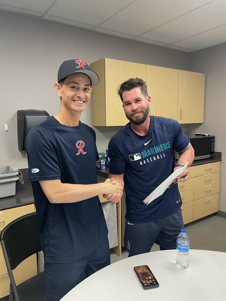 渡米4年目、ついにタコマ・レイニアーズのクラブハウスで契約を結んだ乙坂。握手を交わすのはタコマのコーチ、ボー・テイラー　写真：本人提供