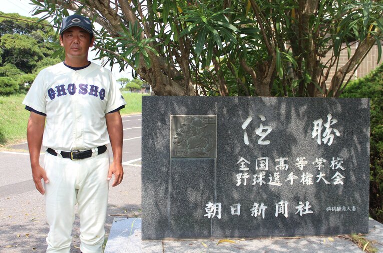 1974年の銚子商高全国制覇の記念碑と、OBの澤田洋一・現監督。公立校の現状は厳しいが、名門復活への意気込みを語った　©Katsuharu Uchida