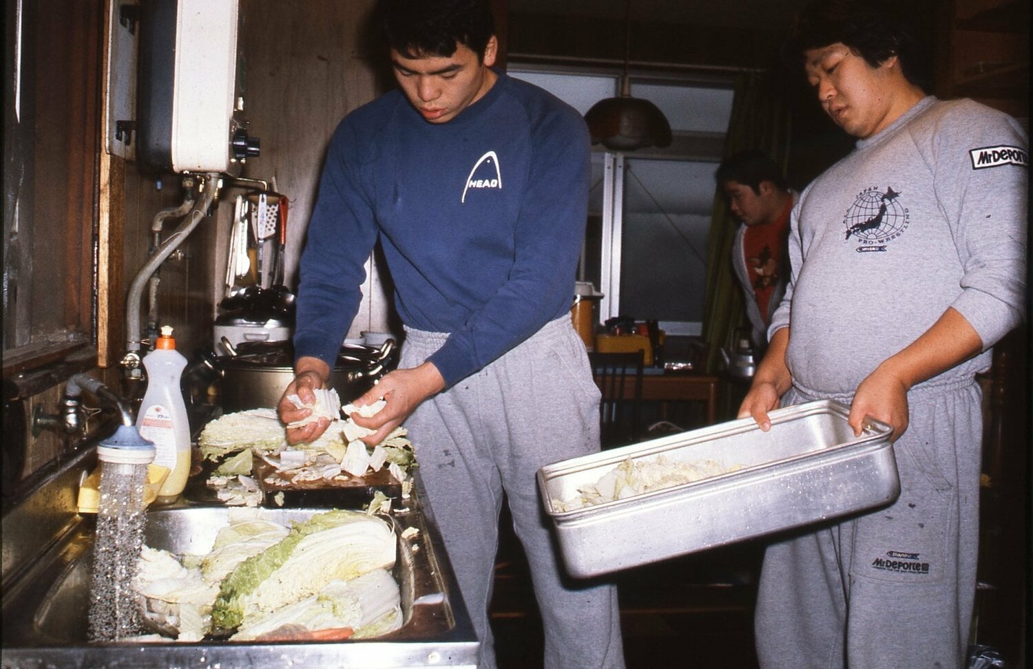全日本プロレス道場で台所で食事の支度をする若き日の三沢光晴（左）と冬木弘道　©︎Moritsuna Kimura/AFLO