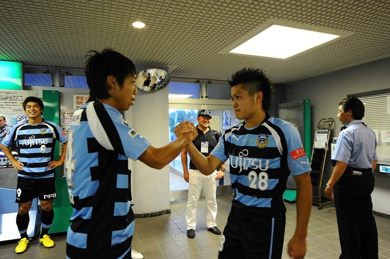 Jリーグデビュー戦を迎える田中とガッチリ握手を交わす中村憲剛　©︎J.LEAGUE
