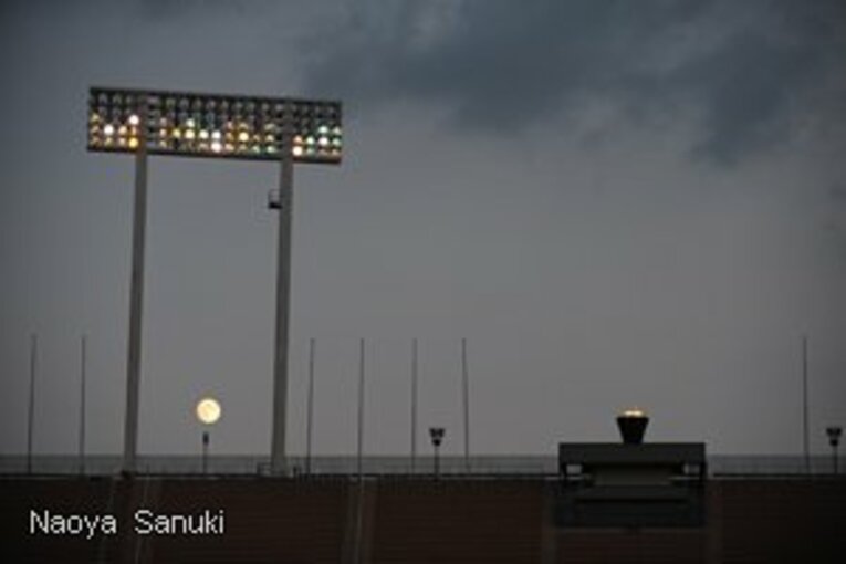 暮れていく国立競技場に灯る聖火と照明