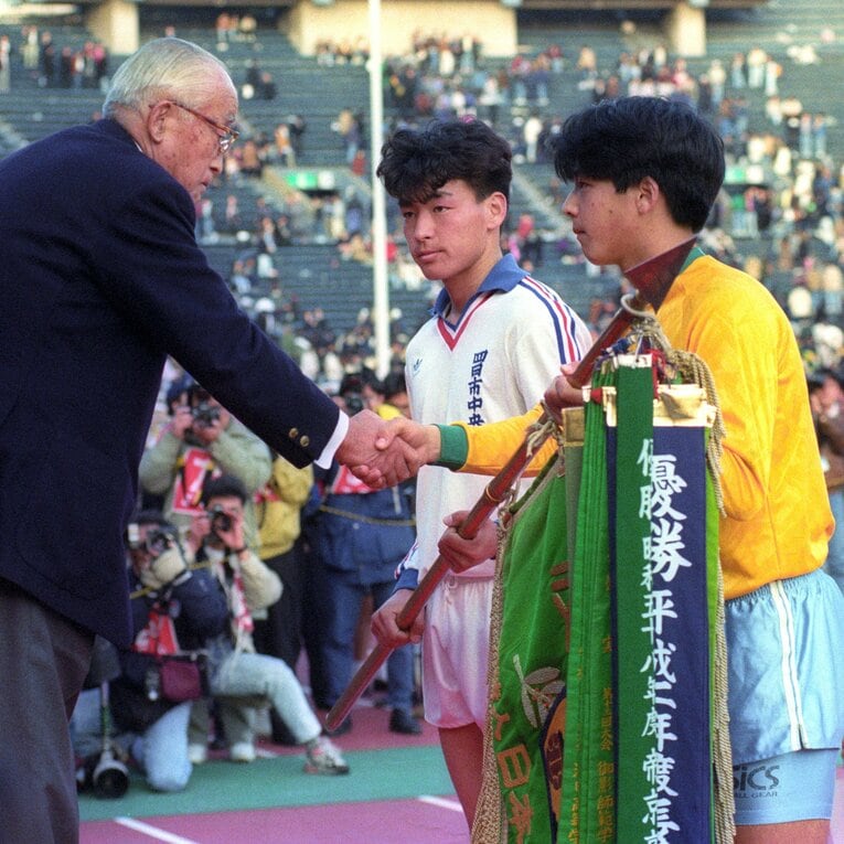 1992年1月の高校サッカー選手権。四日市中央工高と同時優勝し、優勝旗を受ける帝京高キャプテン・日比威　©KYODO
