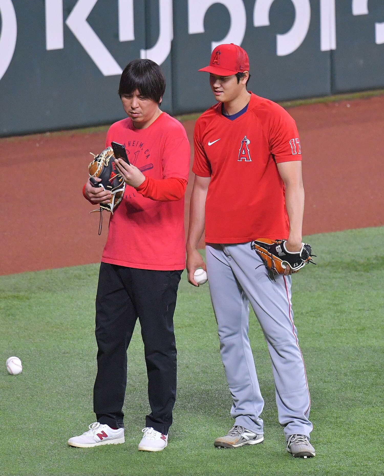 水原通訳とスマホでフォームのチェックを行う大谷　©JIJI PRESS