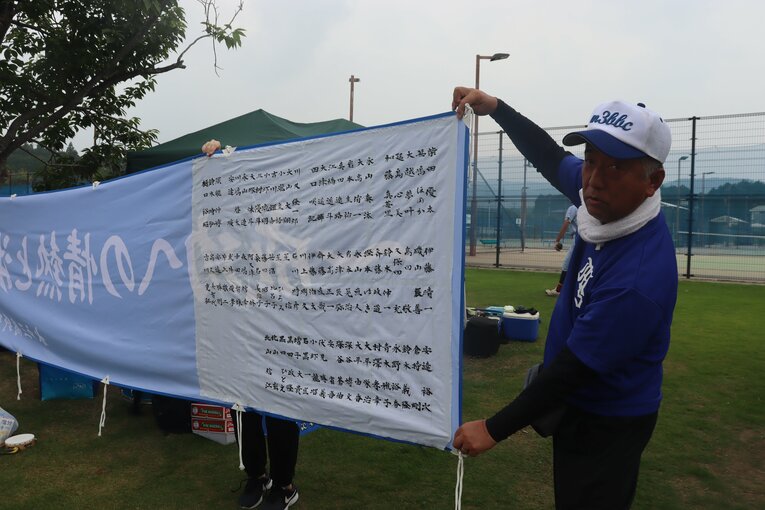 サポーターズ名前入り横断幕を見せる大高正一保護者会長　©Yuki Kashimoto