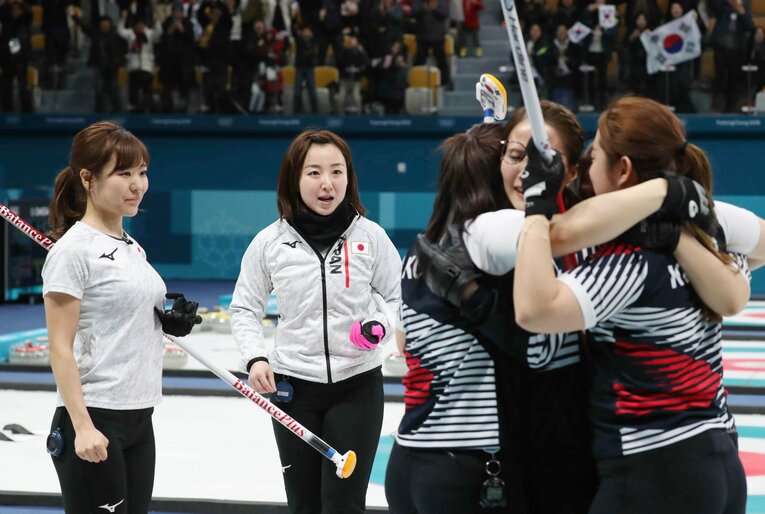 平昌五輪カーリング女子準決勝で、延長戦の末に韓国に敗れ、厳しい表情の（左から）吉田知那美、藤沢五月。右は喜ぶ韓国チーム　©︎JIJI PRESS
