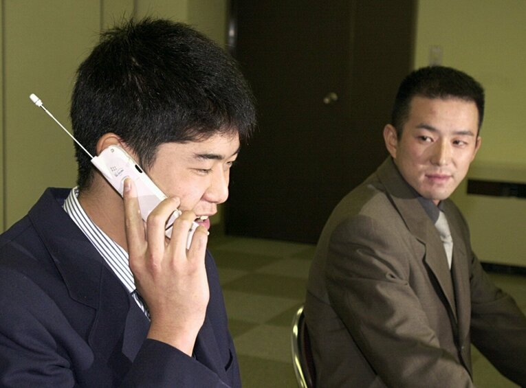 2000年11月17日、ドラフト会議でオリックスから1位指名された内海哲也。携帯電話で仰木彬監督と言葉を交わす　©JIJI PRESS