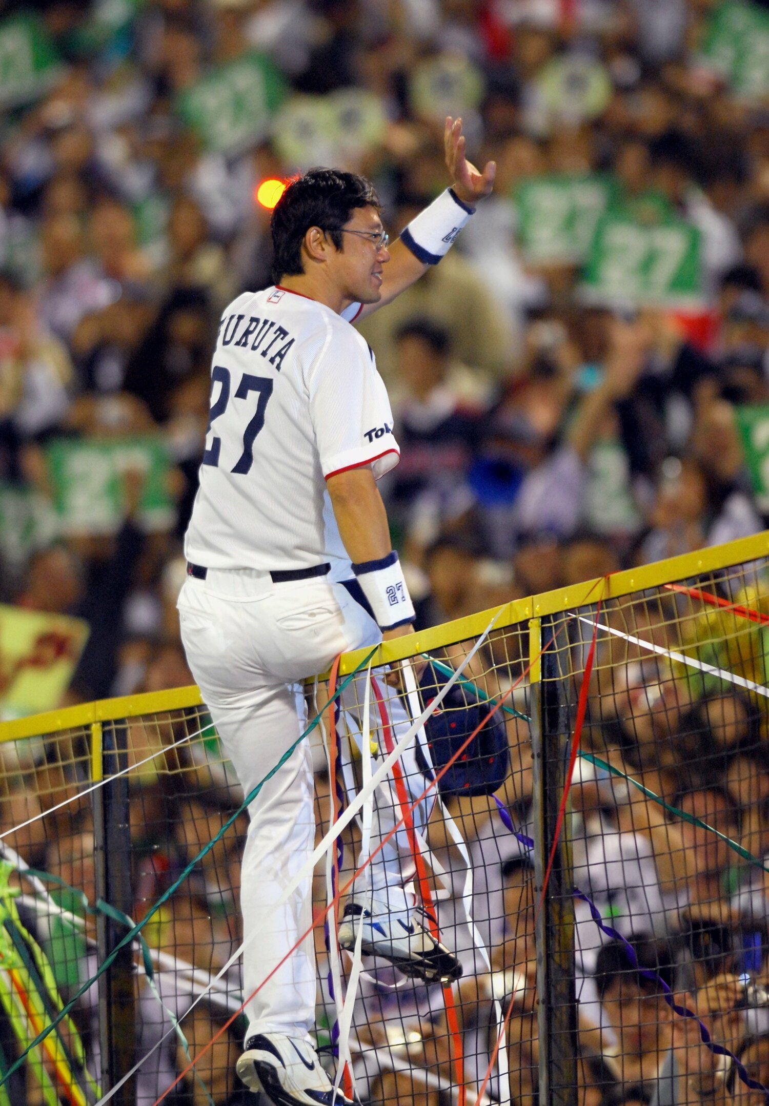 引退試合後に外野スタンドのフェンスに登り、ヤクルトファンの声援に応える古田　©︎JIJI PRESS