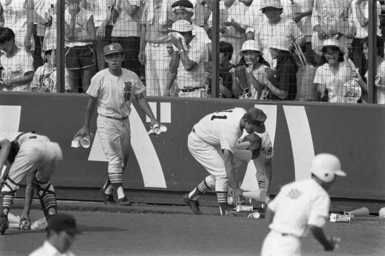 グラウンドに投げ込まれたコップやメガホンを拾う星稜の選手たち　©JIJI PRESS