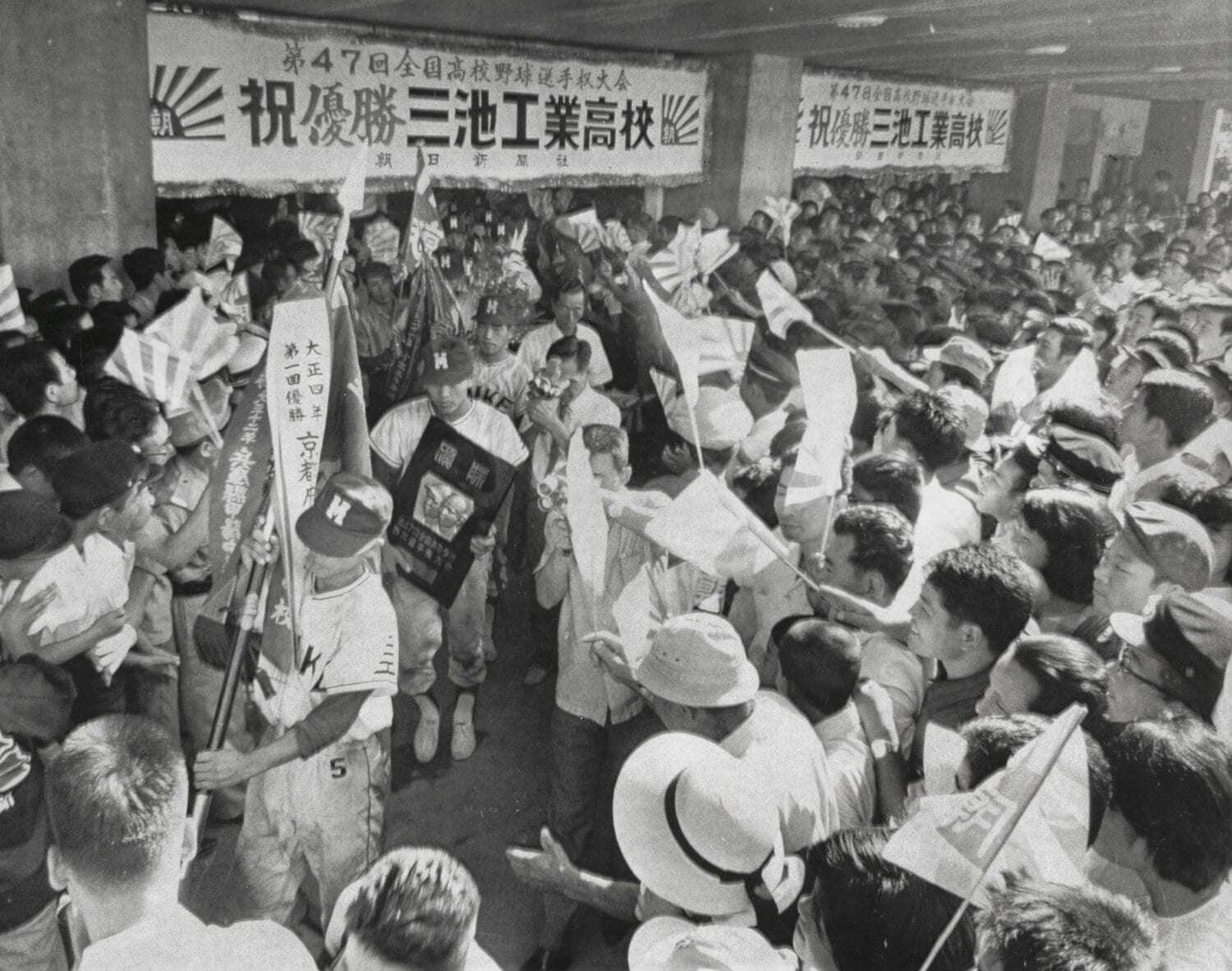 1965年夏の甲子園で優勝した三池工業ナイン。小倉駅に到着し、大優勝旗を先頭に大勢の出迎えの人波を進む。この光景は少年時代の原辰徳の原風景でもあるという ©︎Asahi Shimbun
