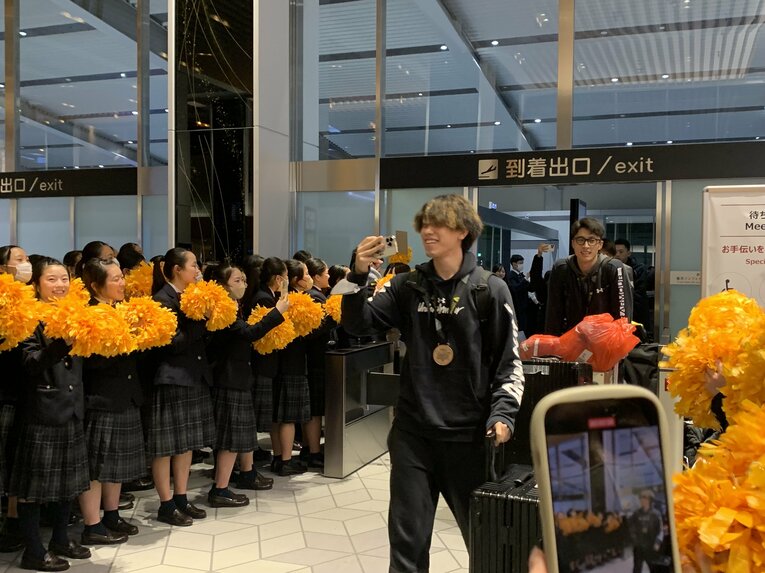 ホームゲームで演技する箕面自由学園高校のチアリーダー部「ゴールデンベアーズ」のお出迎えに笑顔の大宅真樹　©︎Noriko Yonemushi