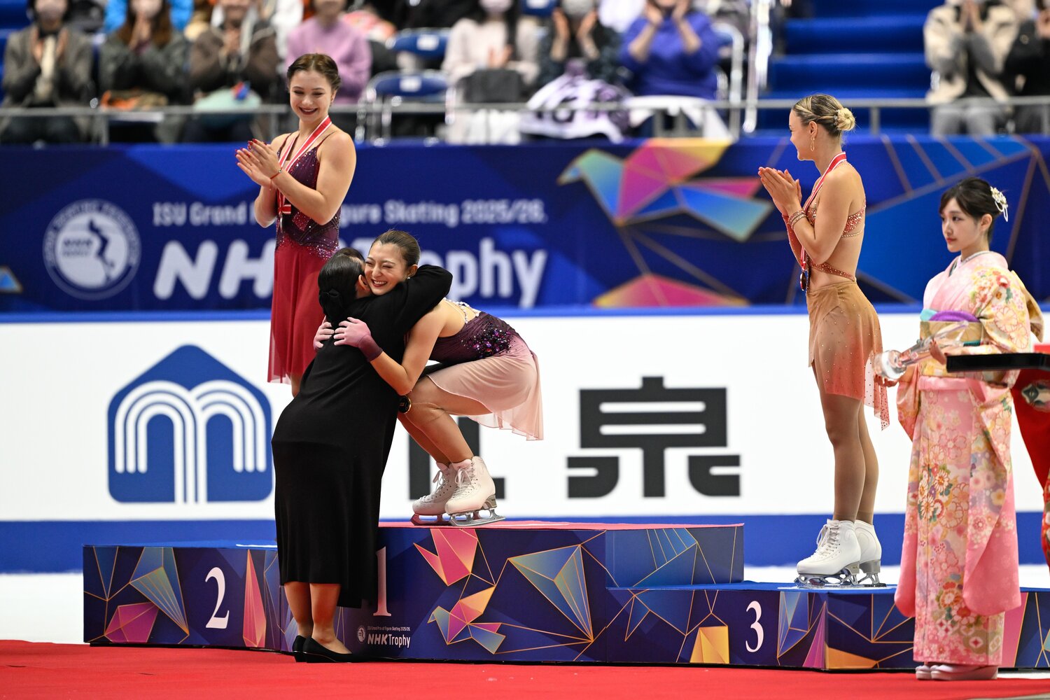NHK杯でプレゼンターの伊藤みどりから金メダルをかけられた後、笑顔でハグをする坂本花織　©️Asami Enomoto