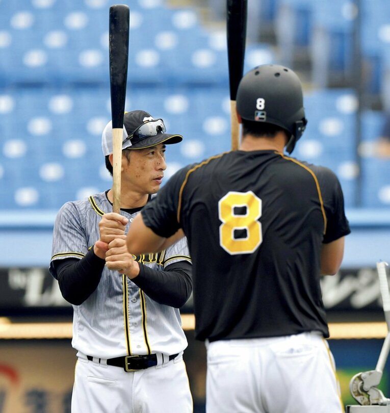 佐藤（手前）を指導する、当時阪神監督の矢野。現役時は中日を経てプレーした阪神で2度の優勝。'19～'22年に阪神で指揮を執り、通算274勝248敗27分　©SANKEI SHIMBUN