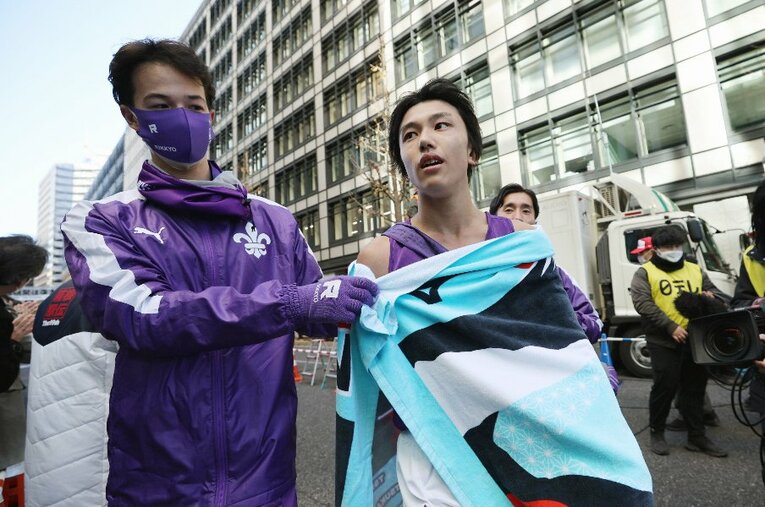 箱根駅伝で55年ぶりにゴールした立教大。アンカーの安藤圭佑（2年）を迎えるキャプテン・ミラー千本真章（4年） ／ photograph by JIJI PRESS