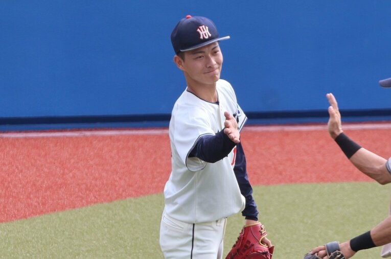 公式戦でチームメイトとハイタッチを交わす花園大の藤原聡大。今年のドラフトで楽天から1位指名を受けた最速156キロの剛腕だ　©Fumi Sawai