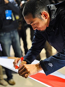 練習拠点の米国に発つ前に、成田で日の丸に「生きろ」というメッセージを書く