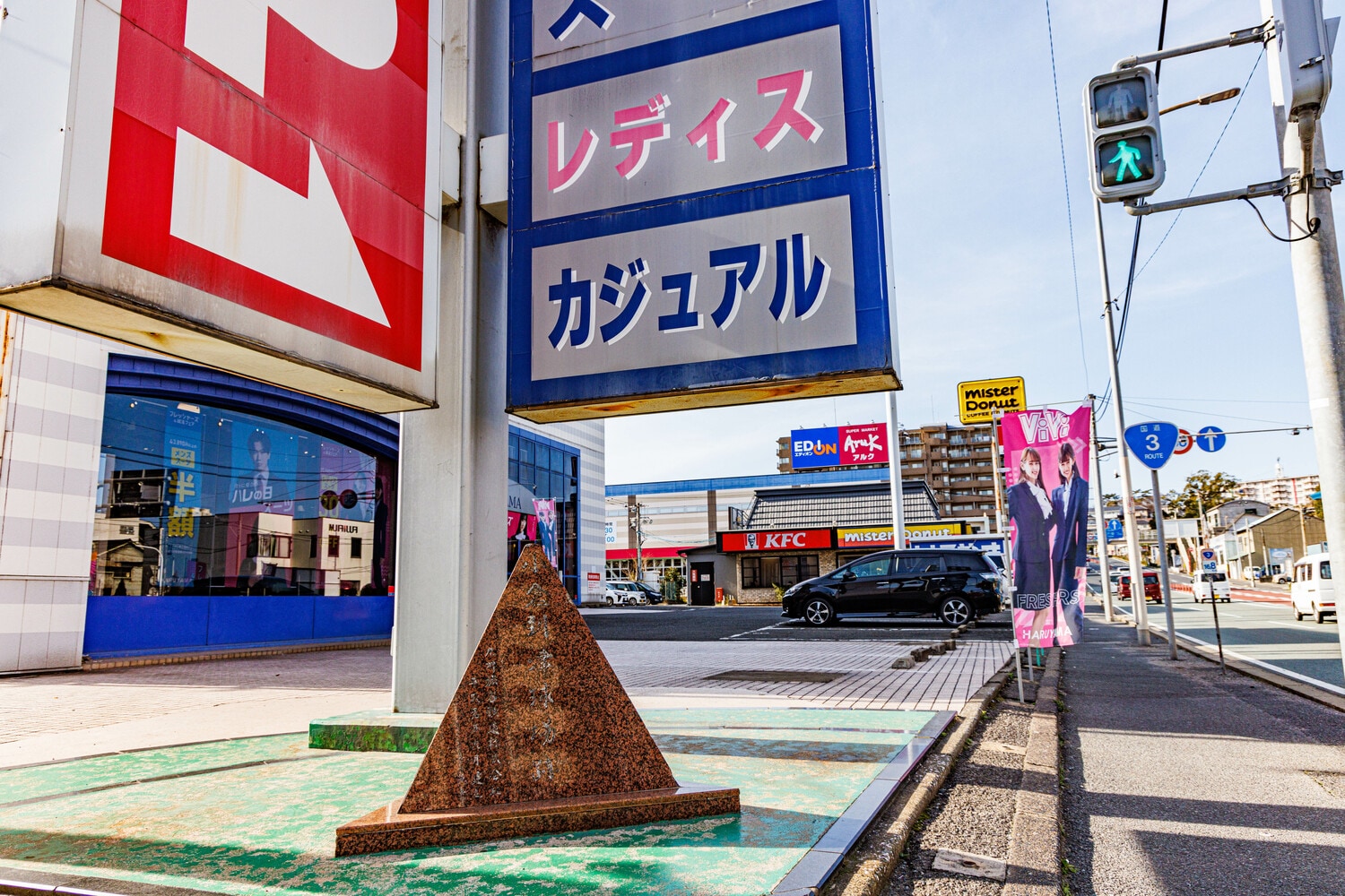 南小倉駅から国道3号を15分ほど歩くと…紳士服のはるやまがあった。その大きな看板の足元にあるのは…「小倉到津球場跡」(写真中央、読みづらいがそう書いてある)の小さな石碑だった ©Masashi Soiri