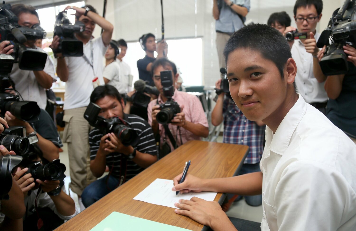 世界選手権から帰国した直後、多くの報道陣に囲まれながらプロ野球志望届に記入する大谷（2012年9月）　©︎Sankei Shimbun